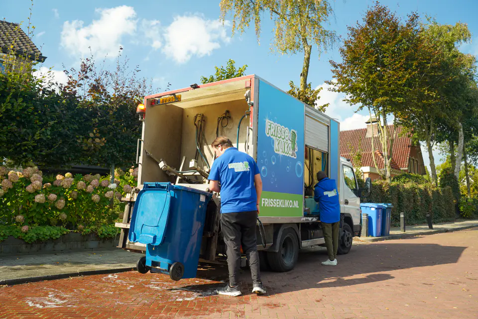 De reinigingswagen van Frisse Kliko staat klaar in een woonstraat bij een container.
